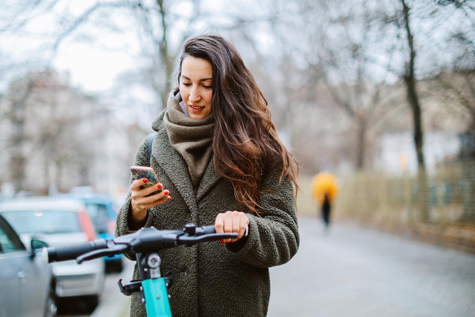 Commuter in Berlin on electronic scooter checking mobile app