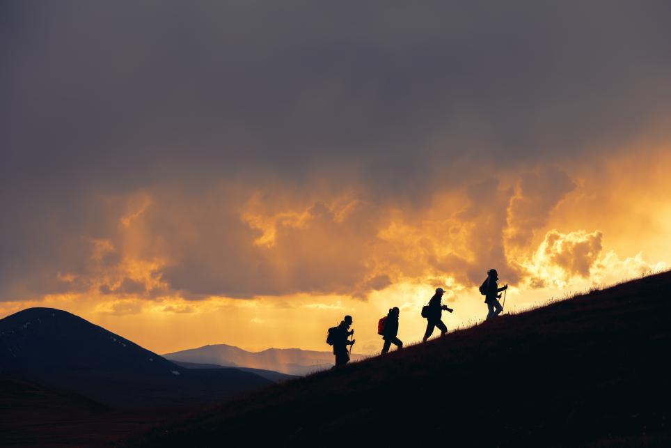 firefighters climbing a mountain with fire in the background